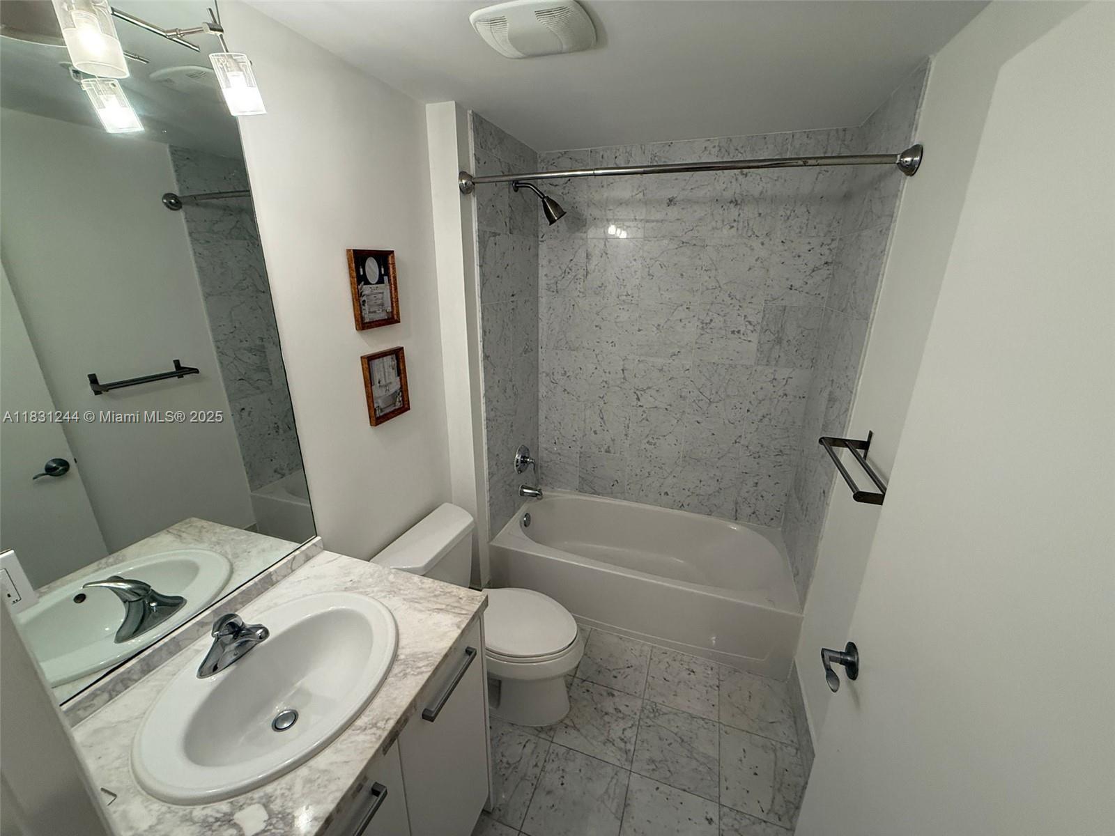 A bathroom features a marble-tiled shower-tub combination, a vanity with a marble countertop, and tile flooring — 244 Biscayne Blvd # 908, Miami FL 33132, MIAMI, FL