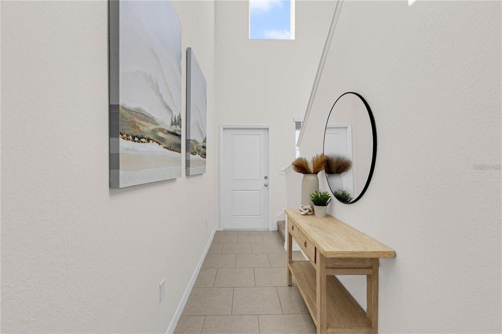 A bright entryway features a wooden console table, a round mirror, and wall art — 13239 TURNLEAF BOULEVARD, PUNTA GORDA, FL