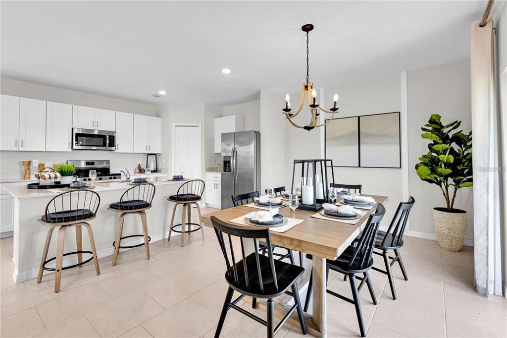 A kitchen with white cabinets and a dining area featuring a wooden table and chandelier — 13239 TURNLEAF BOULEVARD, PUNTA GORDA, FL