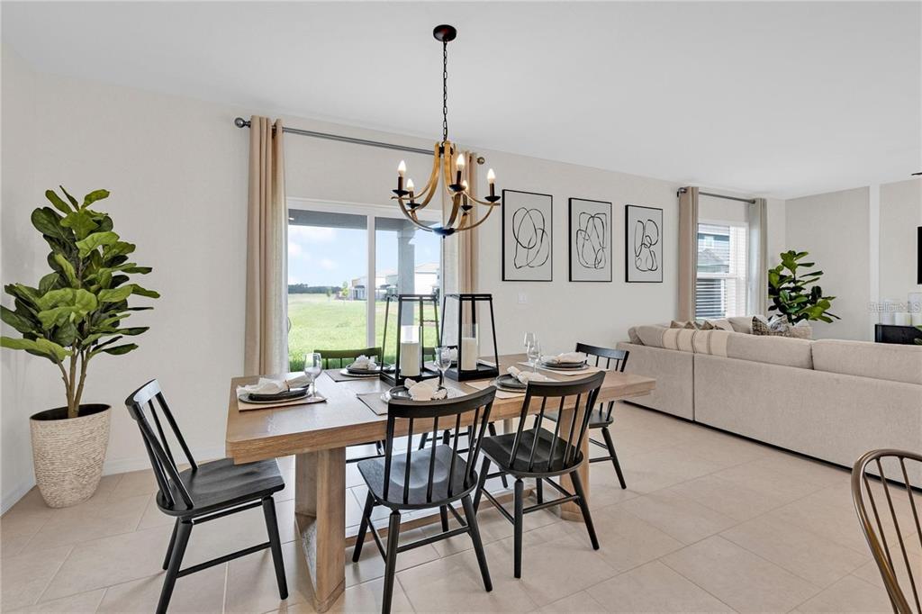 A dining area features a wooden table, black spindle chairs, and a chandelier near sliding doors — 13239 TURNLEAF BOULEVARD, PUNTA GORDA, FL