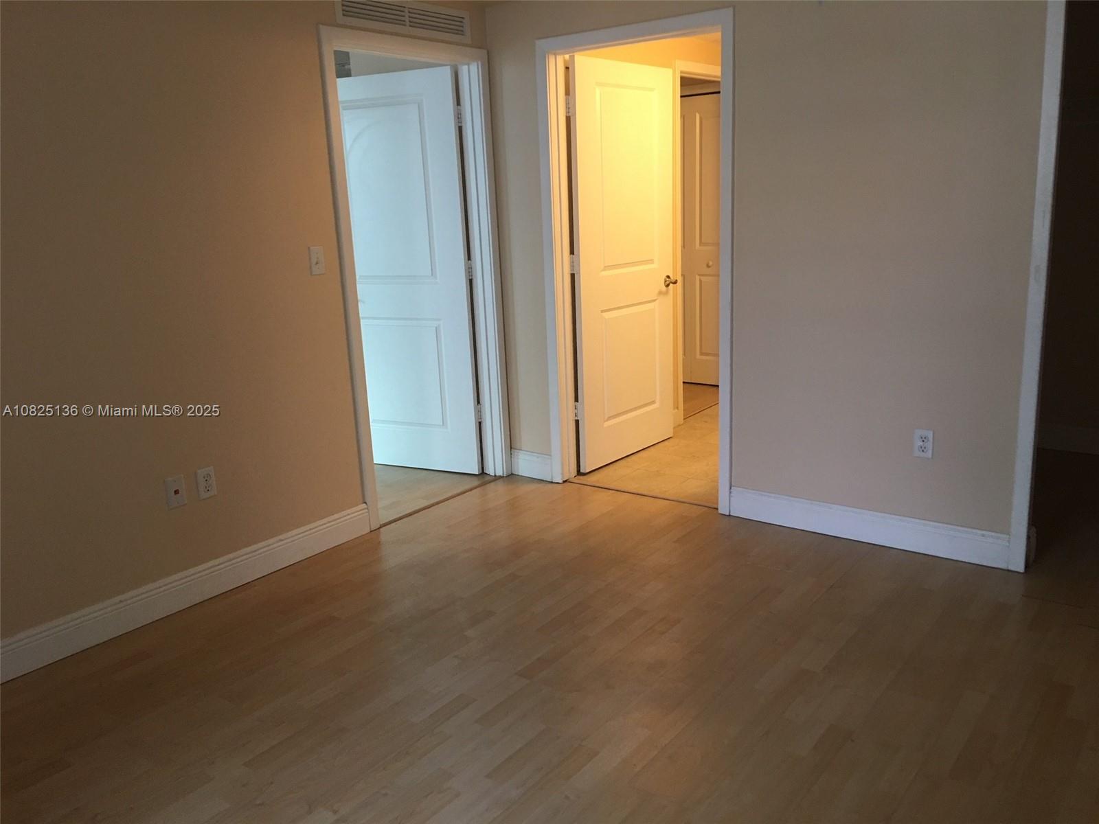 An interior room features light-colored walls, wood-look flooring, and two open doorways leading elsewhere — 170 SE 14th St # 1407, Miami FL 33131, MIAMI, FL
