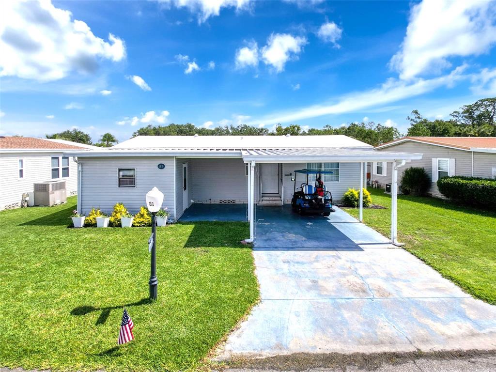 A single-story house features a light gray exterior, a covered carport, and a front lawn — 81 STRAPHMORE DRIVE, HAINES CITY, FL