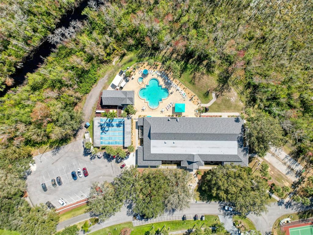 An aerial view shows a community clubhouse with a swimming pool, tennis court, and parking — 81 STRAPHMORE DRIVE, HAINES CITY, FL
