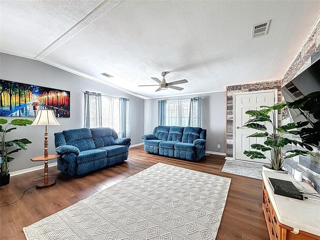 A living room features two blue sofas, a patterned rug, and wood-look flooring — 81 STRAPHMORE DRIVE, HAINES CITY, FL