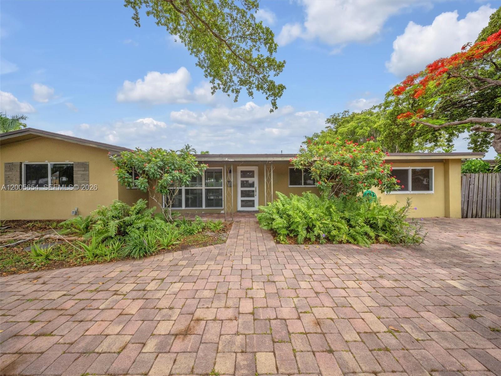 An open-concept kitchen and living area features wood cabinetry, stainless steel appliances, and light flooring — 4401 NE 15th Ter, Oakland Park FL 33334, OAKLAND PARK, FL