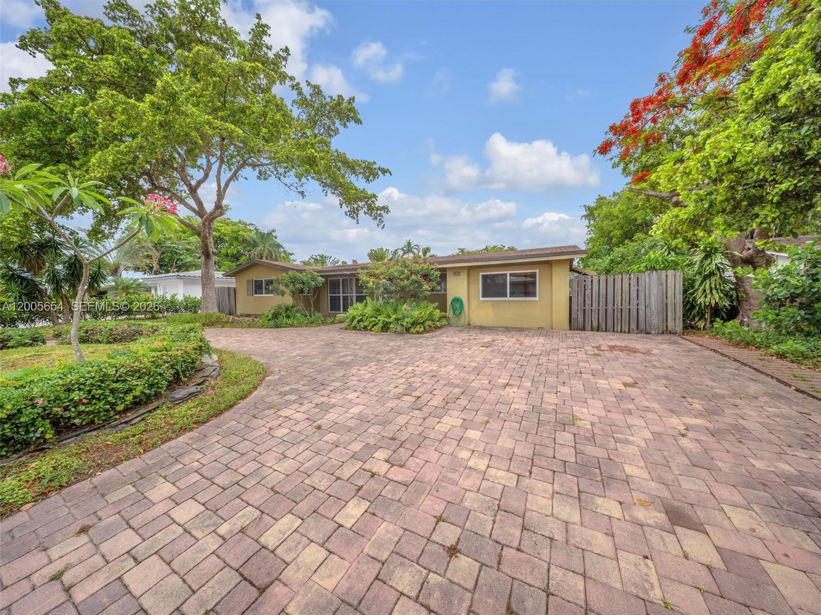 A kitchen features wood cabinets, stainless steel appliances, granite countertops, and light hardwood flooring — 4401 NE 15th Ter, Oakland Park FL 33334, OAKLAND PARK, FL