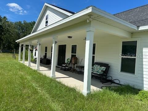 A white house with a large covered porch featuring columns and outdoor seating — 5040 NE 48TH COURT, HIGH SPRINGS, FL