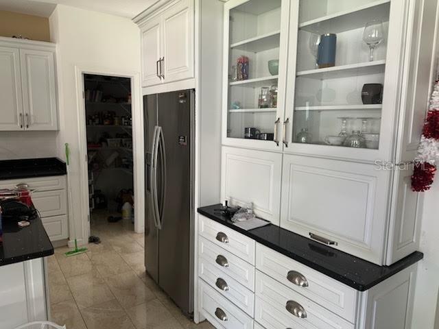 A kitchen features white cabinetry, black countertops, a stainless steel refrigerator, and a walk-in pantry — 5040 NE 48TH COURT, HIGH SPRINGS, FL