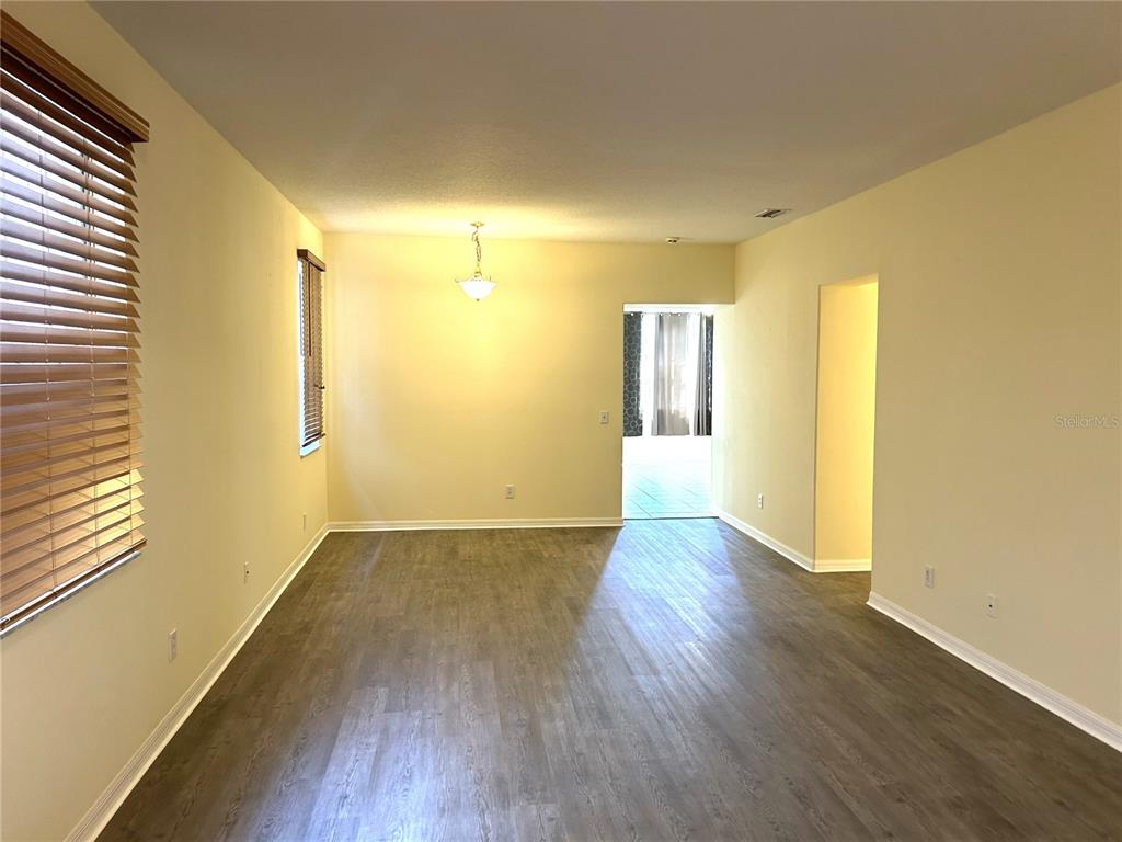 A room with wood-look flooring, a tiled entryway, a front door, and window blinds — 11164 GOLDEN SILENCE DRIVE, RIVERVIEW, FL