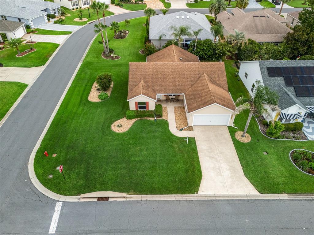An aerial view of a suburban house with a brown roof, driveway, and landscaped lawn — 1502 AQUINO LANE, THE VILLAGES, FL