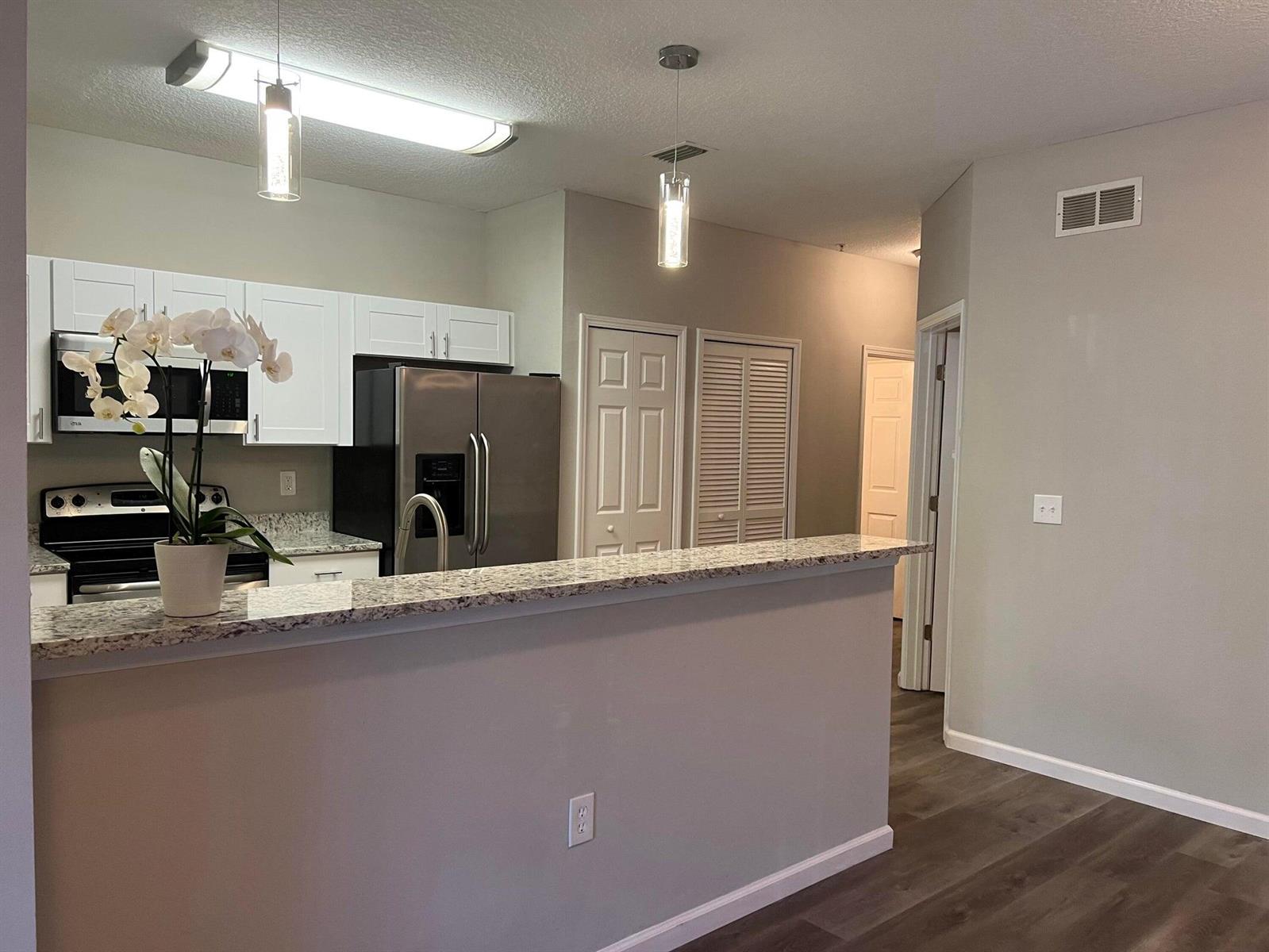 A kitchen features white cabinets, stainless steel appliances, granite countertops, and a breakfast bar — 4998 Key Lime Drive # 105, Jacksonville FL 32256, JACKSONVILLE, FL