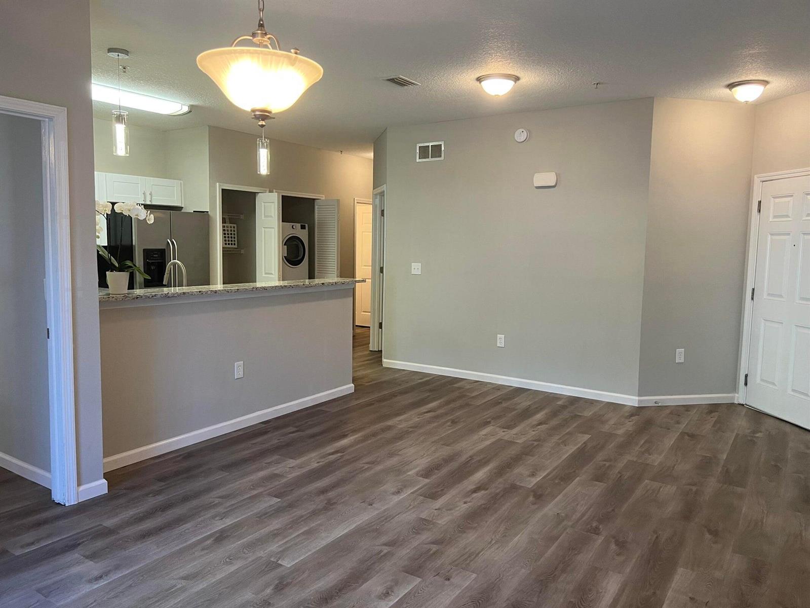An open-concept living area features wood-look flooring, a kitchen breakfast bar, and neutral walls — 4998 Key Lime Drive # 105, Jacksonville FL 32256, JACKSONVILLE, FL