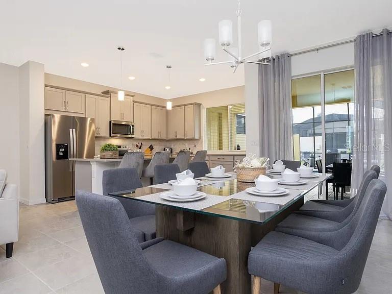 A dining area with a glass-topped table and gray chairs sits beside a modern kitchen — 2182 FLEMING MIST PLACE, KISSIMMEE, FL