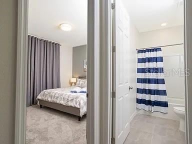 A view through a doorway showing a bedroom with a bed and an adjacent bathroom — 2182 FLEMING MIST PLACE, KISSIMMEE, FL