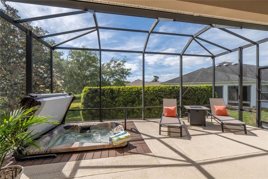 A screened-in patio features a hot tub on a wooden deck and two lounge chairs — 270 MATISSE AVENUE, THE VILLAGES, FL