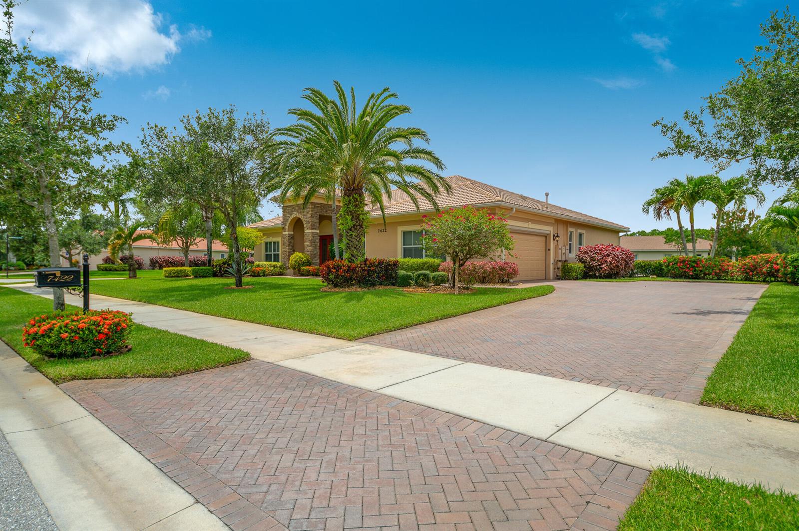 A single-story house with a brick-paved driveway, a palm tree, and a manicured lawn — 7422 SE Belle Maison Drive, Stuart FL 34997, STUART, FL