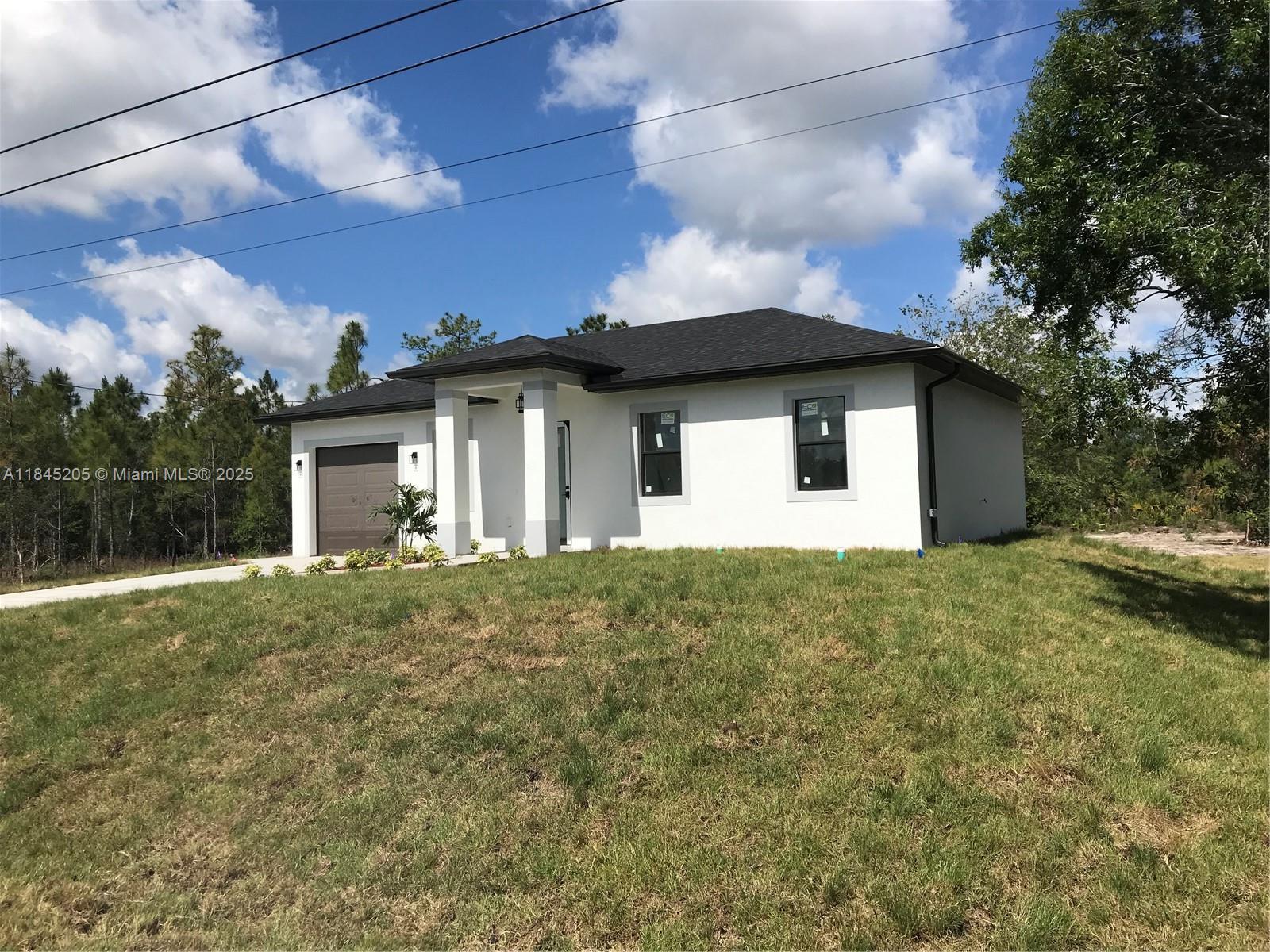 A single-story white house with a dark roof and a one-car garage — 919 Glenn Ave, Lehigh Acres FL 33972, LEHIGH ACRES, FL