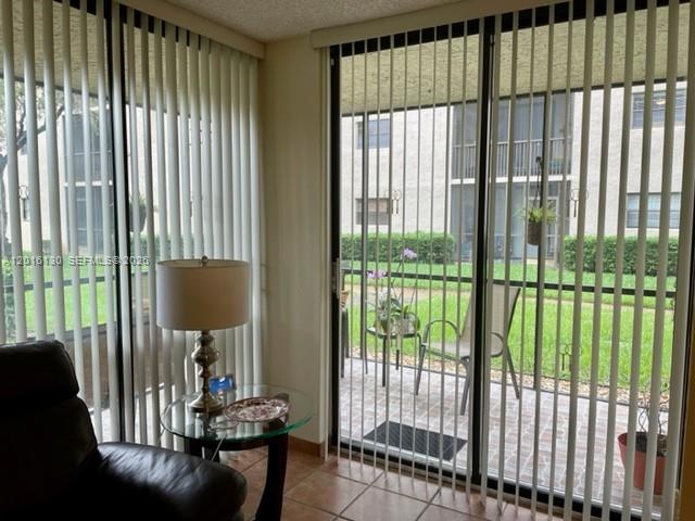A living room features a dark leather chair, a glass side table, and vertical blinds — PLANTATION, FL