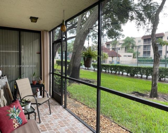 A screened-in patio features tiled flooring, a chair, and a view of a grassy area — PLANTATION, FL