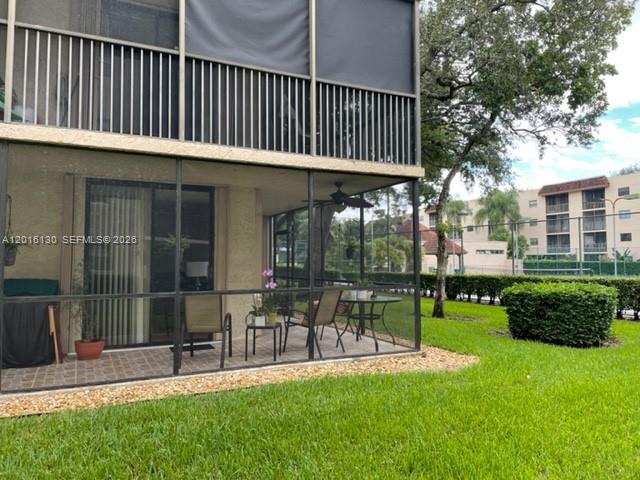 A ground-floor screened-in patio features a table, chairs, and a view of a grassy lawn — PLANTATION, FL