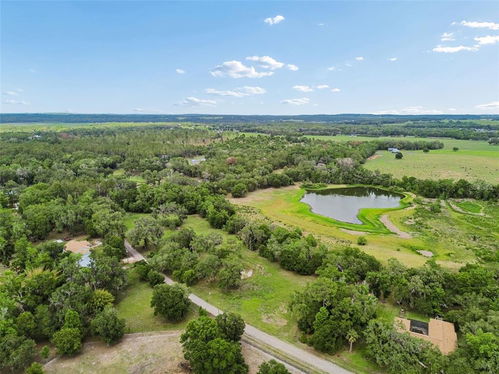 An aerial view shows a rural property with a pond, trees, and two houses — 000 PALOMINO LAKES DR, DADE CITY, FL