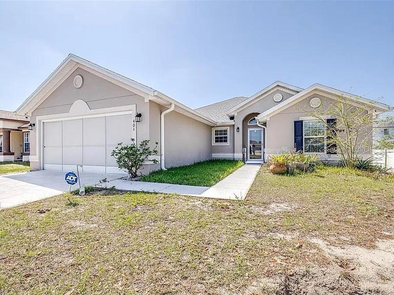 A single-story house with a light-colored stucco exterior, a two-car garage, and a front walkway — 404 RIO GRANDE COURT, POINCIANA, FL