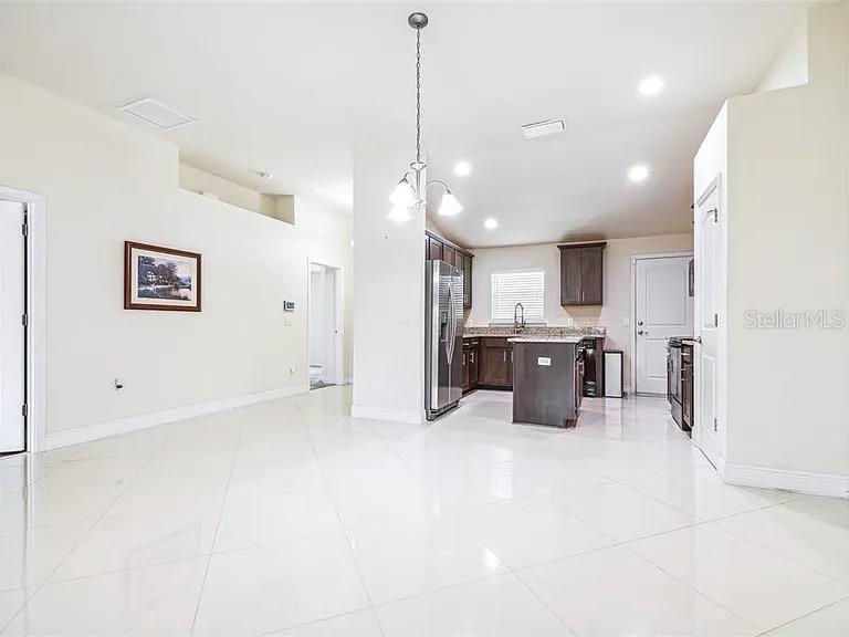 A kitchen with dark cabinets and a center island opens into a tiled dining area — 404 RIO GRANDE COURT, POINCIANA, FL
