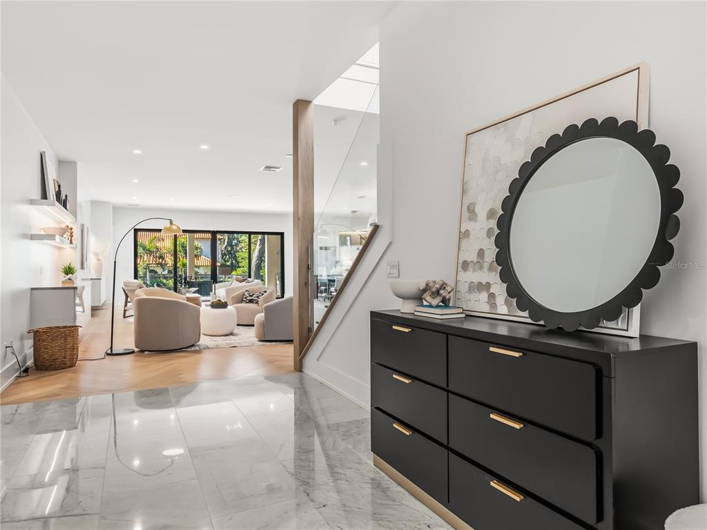 A modern entryway with marble flooring leads into a living room with hardwood floors — 1821 ENGLEWOOD ROAD, WINTER PARK, FL