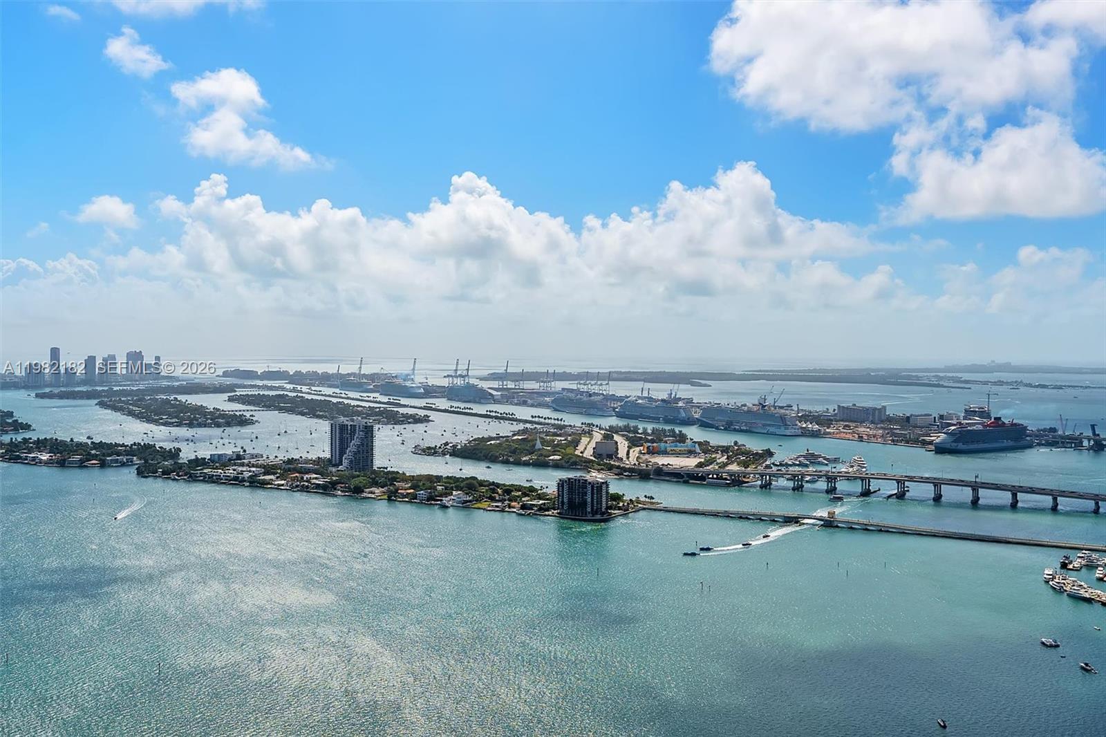 An aerial view shows a harbor with cruise ships, bridges, and islands under a blue sky — 700 NE 24rd St # 5802, Miami FL 33137, MIAMI, FL