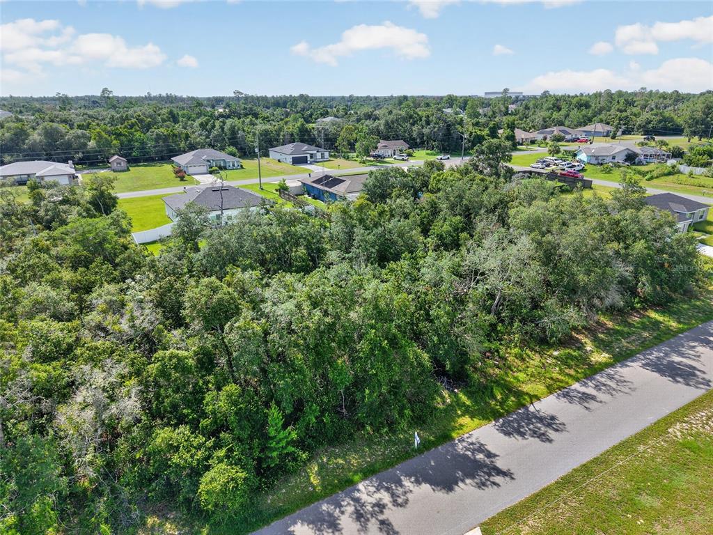 An aerial view shows a wooded vacant lot situated next to a paved residential street — 0000 SW 42ND TERRACE, OCALA, FL