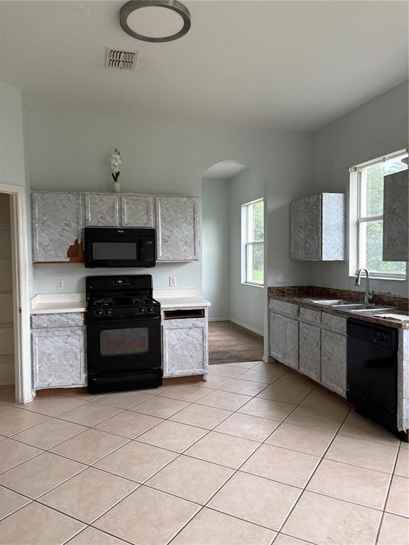 A kitchen features black appliances, marble-patterned cabinet coverings, and light-colored floor tiles — 19939 TAMIAMI AVENUE, TAMPA, FL