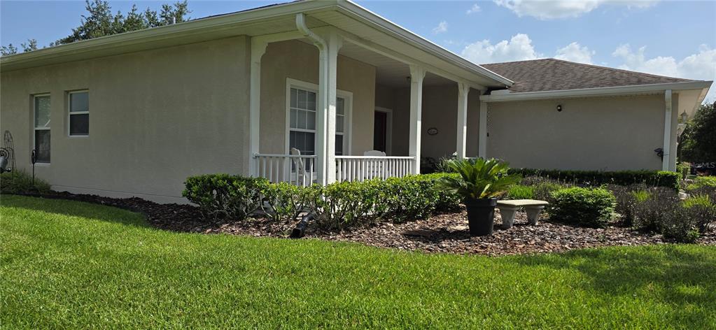 The exterior of a single-story house features a covered porch with white railings and landscaping — 501 HERITAGE TRAIL STREET, POINCIANA, FL