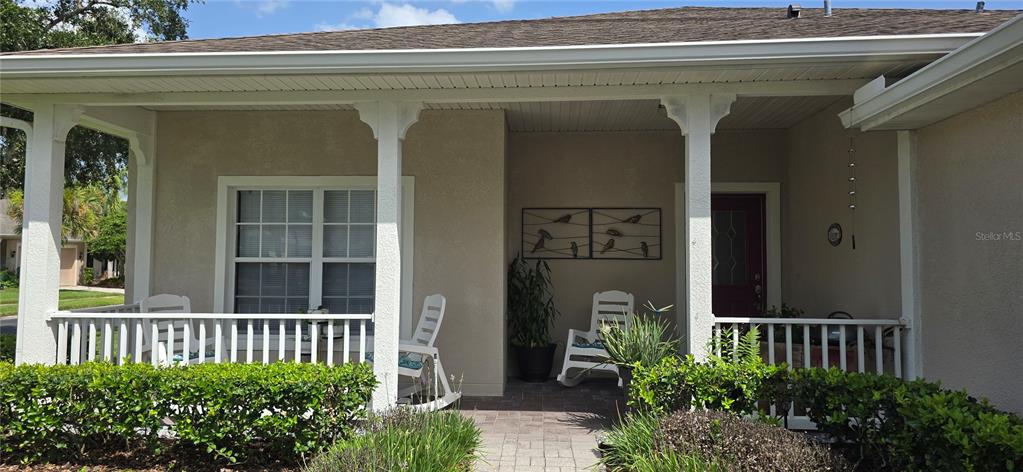 A covered front porch features a white railing, rocking chairs, and a red front door — 501 HERITAGE TRAIL STREET, POINCIANA, FL