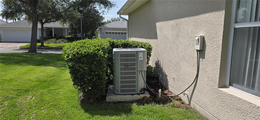 An outdoor air conditioning unit sits on a concrete pad next to a house wall — 501 HERITAGE TRAIL STREET, POINCIANA, FL