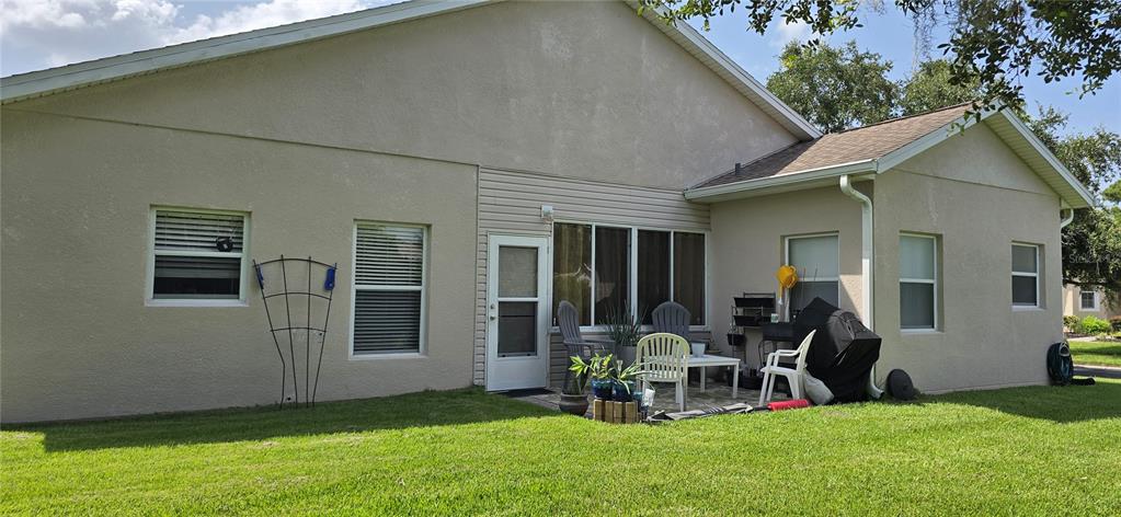 The exterior of a beige stucco house features a small patio with outdoor furniture — 501 HERITAGE TRAIL STREET, POINCIANA, FL