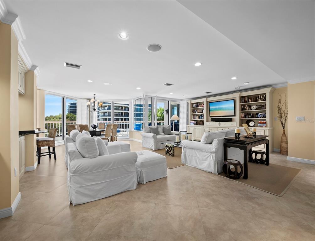 A spacious living room features white slipcovered furniture, tile flooring, and a built-in entertainment center — 455 LONGBOAT CLUB ROAD UNIT 402, LONGBOAT KEY, FL