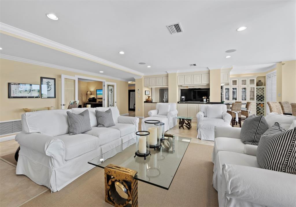 A bright living room features white slipcovered sofas, a glass coffee table, and a wet bar — 455 LONGBOAT CLUB ROAD UNIT 402, LONGBOAT KEY, FL