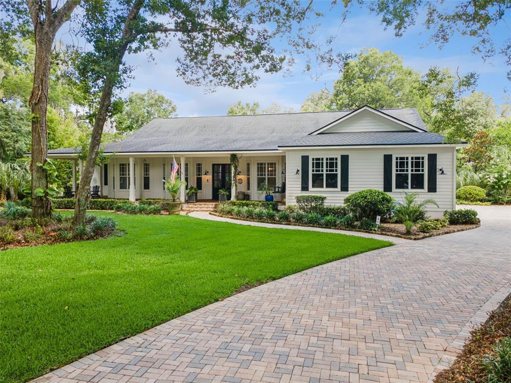 A white single-story house with a brick driveway and a covered front porch — 5002 MUIR WAY, LITHIA, FL