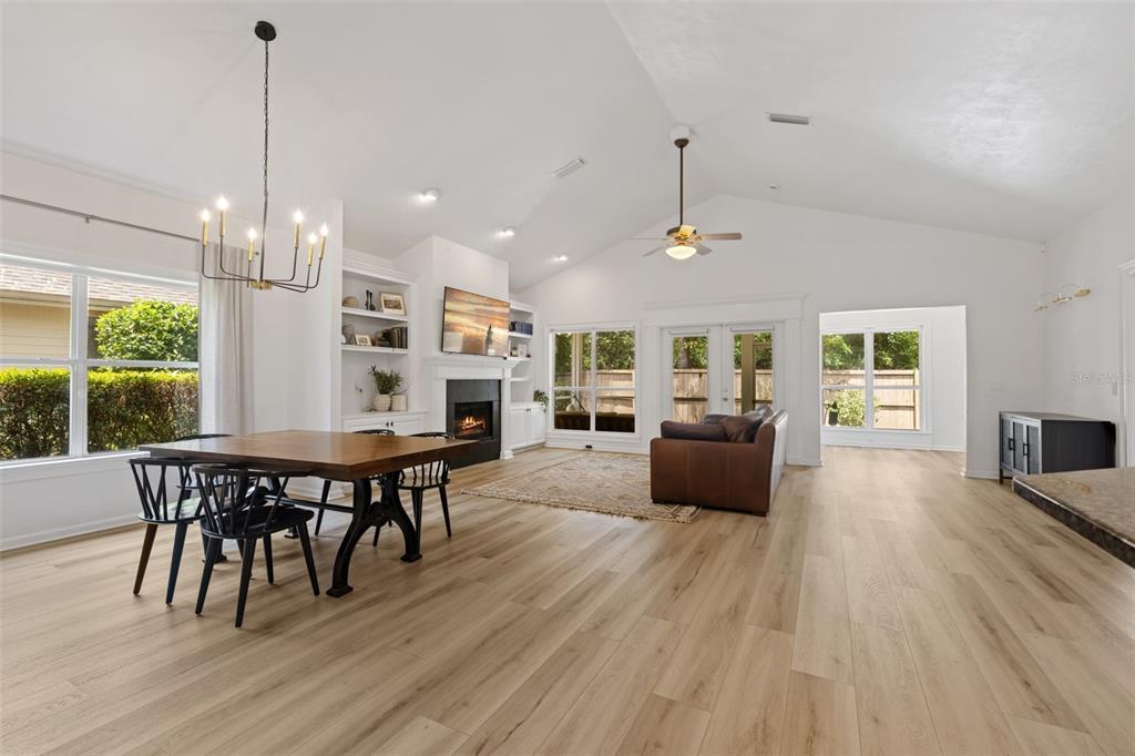 A bright, open-concept living and dining area features vaulted ceilings, light wood flooring, and a fireplace — 3033 SW 98TH DRIVE, GAINESVILLE, FL