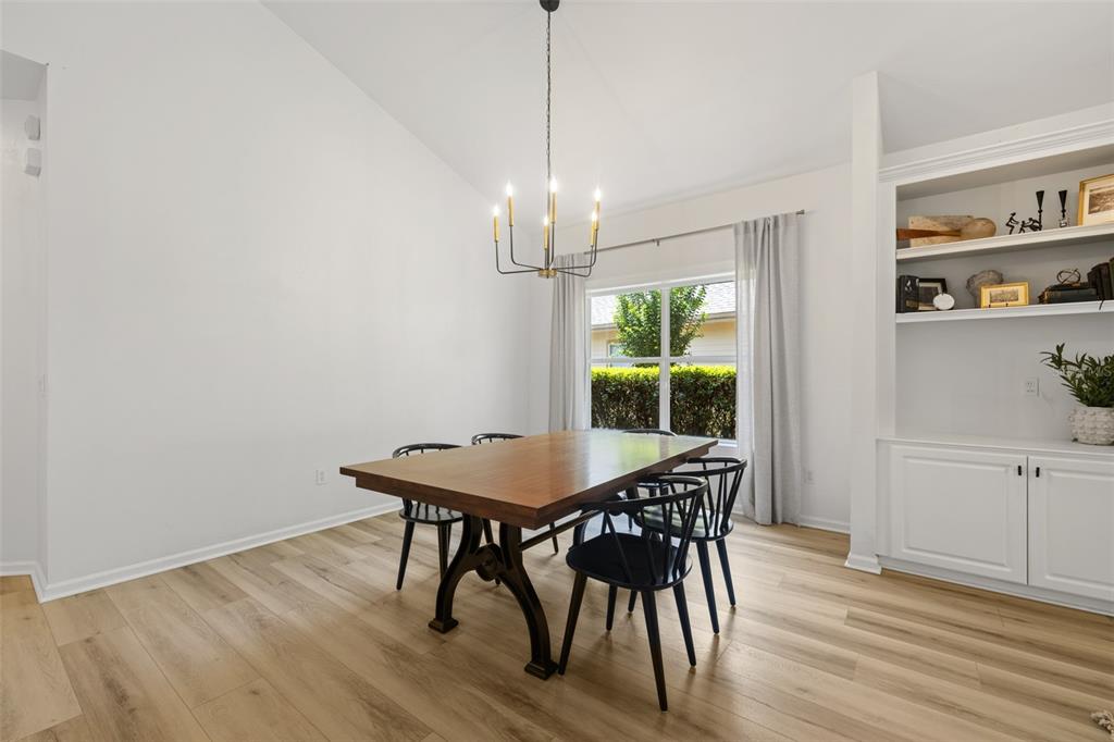A dining room with a wooden table, black chairs, a chandelier, and built-in white shelving — 3033 SW 98TH DRIVE, GAINESVILLE, FL