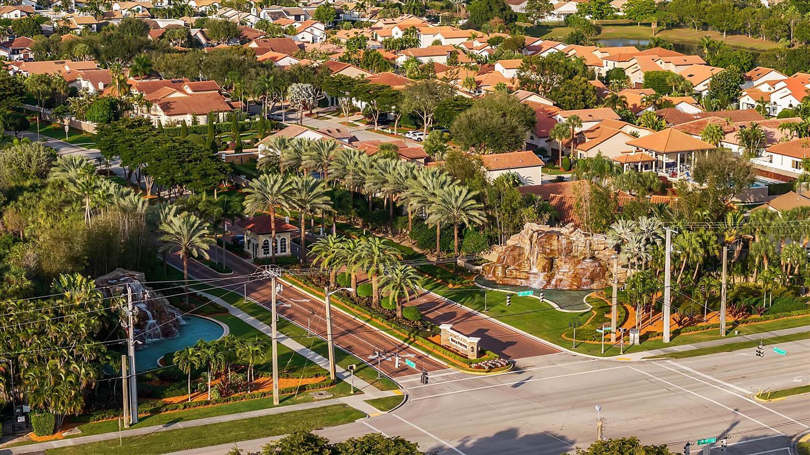 An aerial view shows the gated entrance of a residential community with decorative rock waterfalls — 6757 Via Regina # 3, Boca Raton FL 33433, BOCA RATON, FL