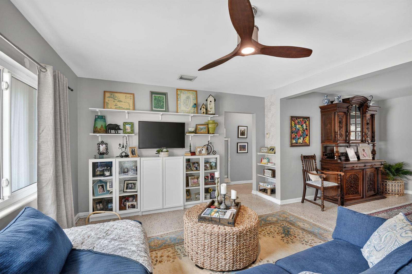 A living room features a blue sectional, a woven coffee table, and a media wall — 338 Edmor Road, West Palm Beach FL 33405, WEST PALM BEACH, FL