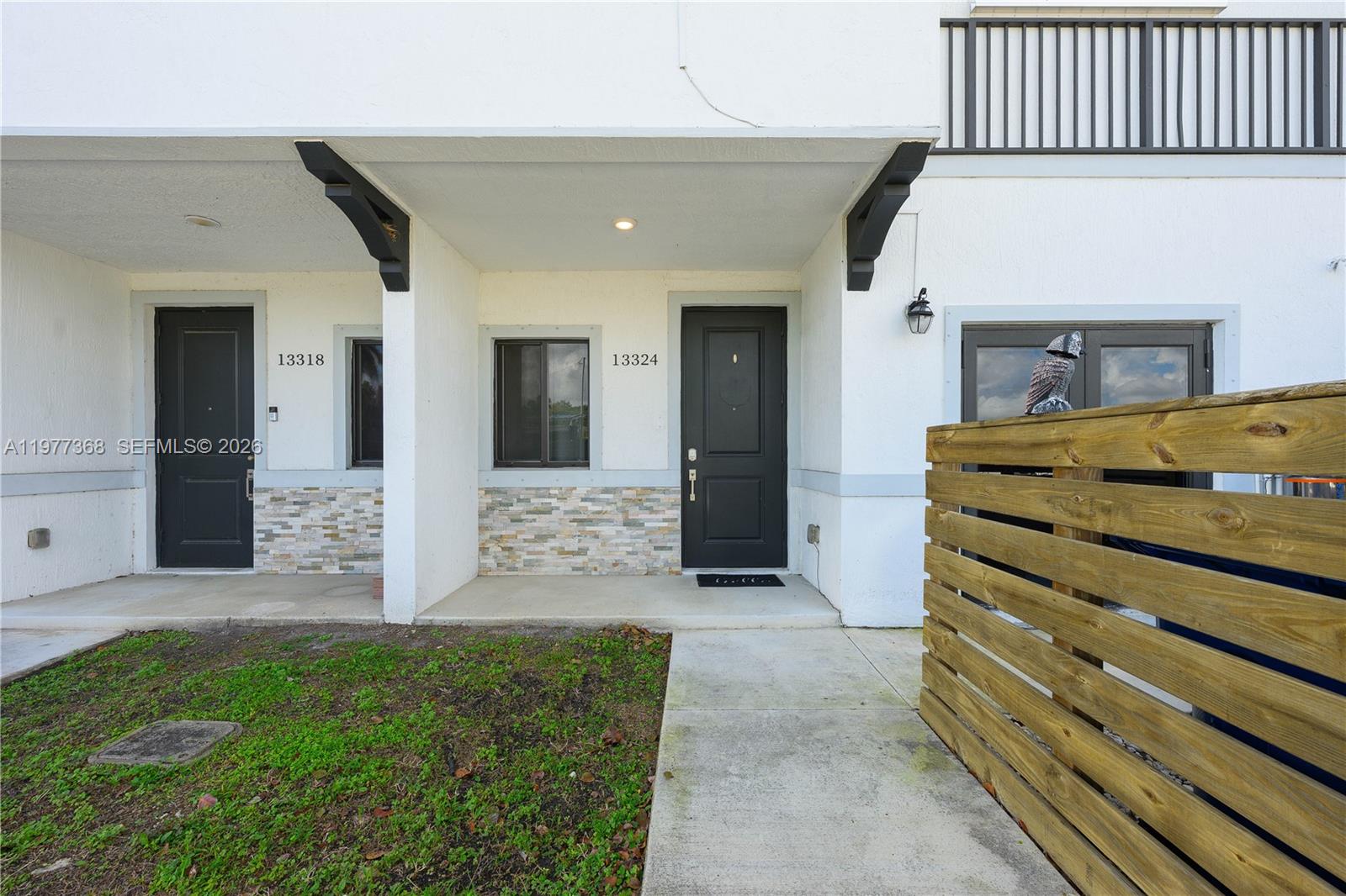 The exterior view shows two adjacent townhouse entrances with black doors and stone veneer accents — 13324 SW 250th St, Miami FL 33032, MIAMI, FL