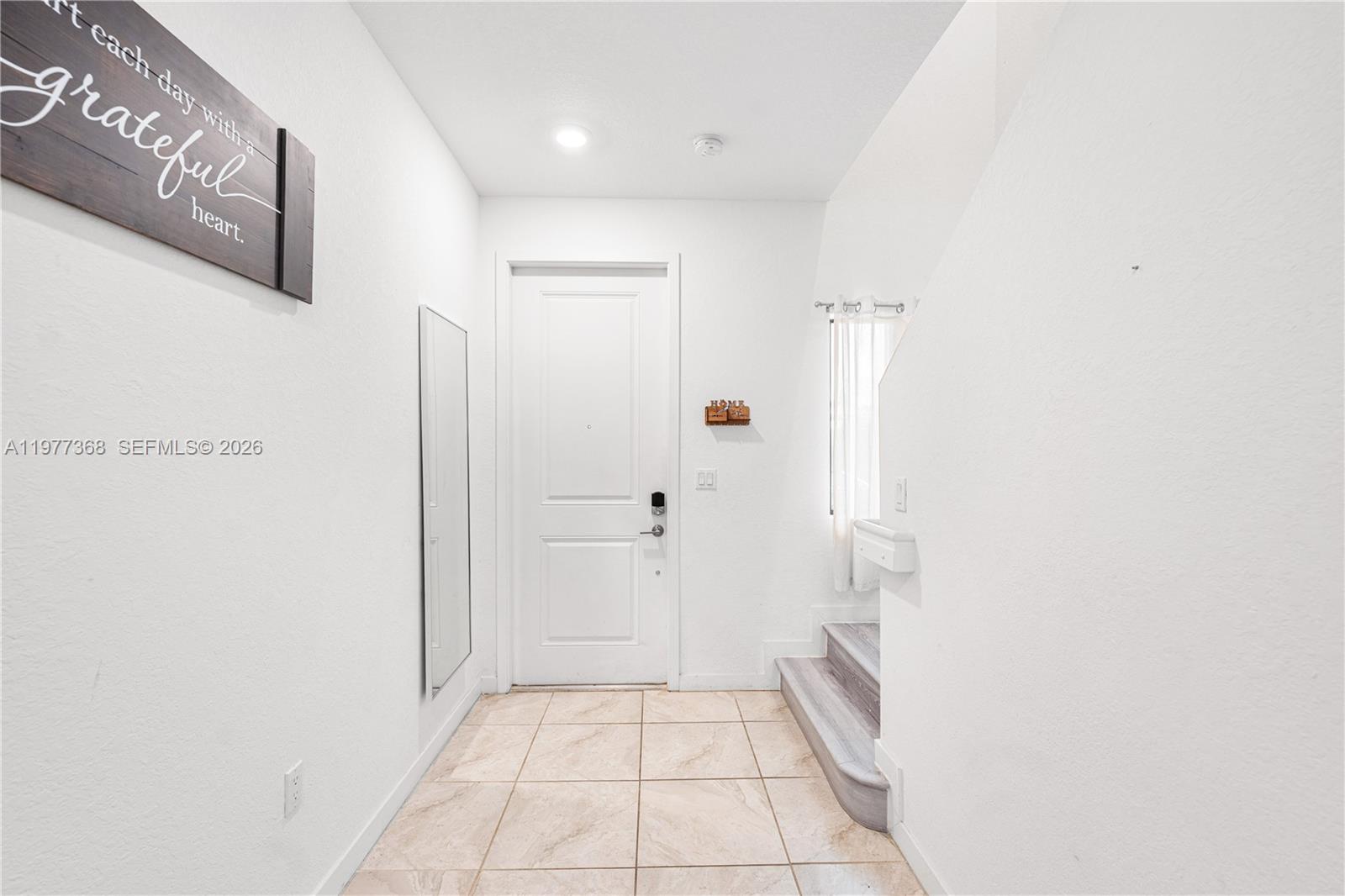 A bright entryway features white walls, tile flooring, a front door, and a staircase — 13324 SW 250th St, Miami FL 33032, MIAMI, FL