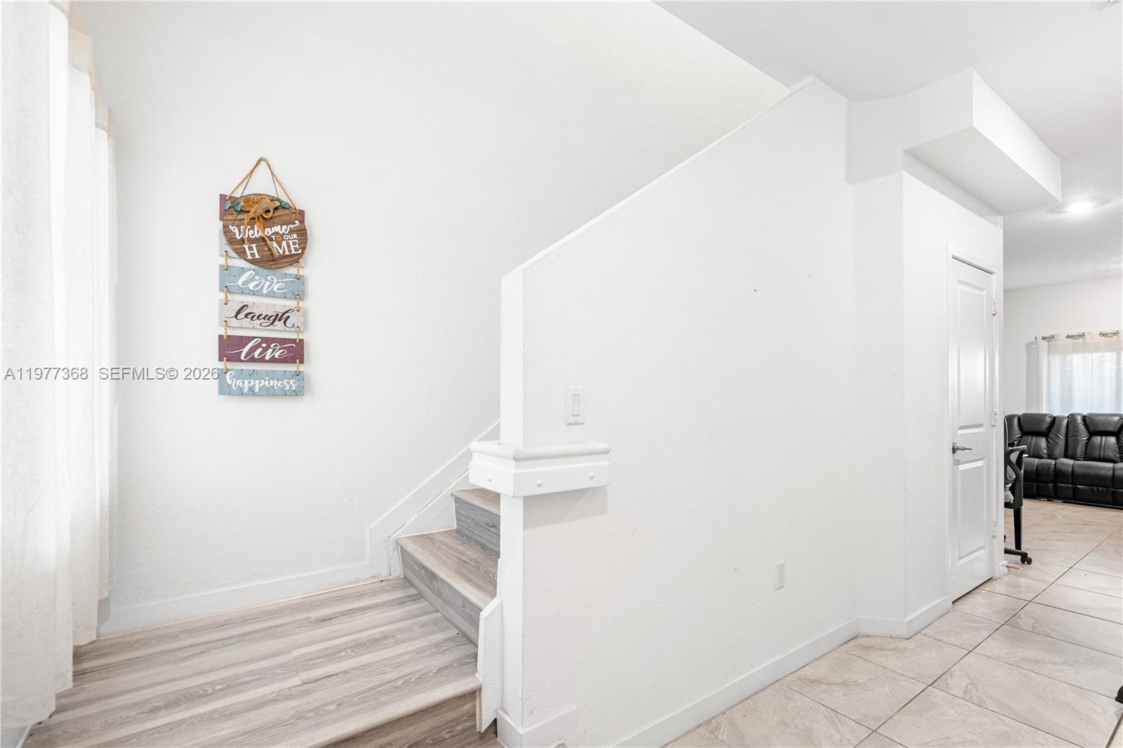 A staircase with wood-look flooring leads upward next to a white wall and tiled floor — 13324 SW 250th St, Miami FL 33032, MIAMI, FL