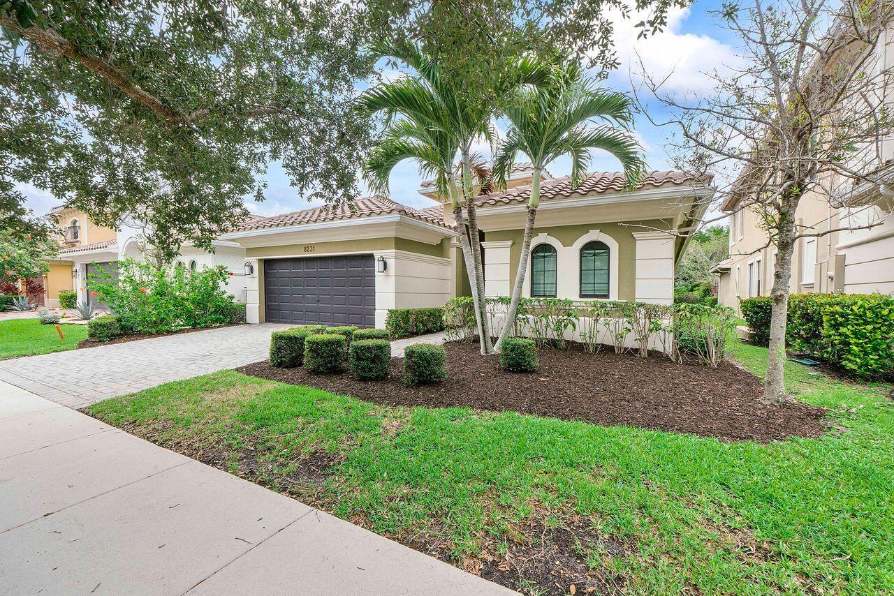 A single-story house with a dark garage door, palm trees, and a landscaped front yard — 8231 Canopy Terrace, Parkland FL 33076, PARKLAND, FL
