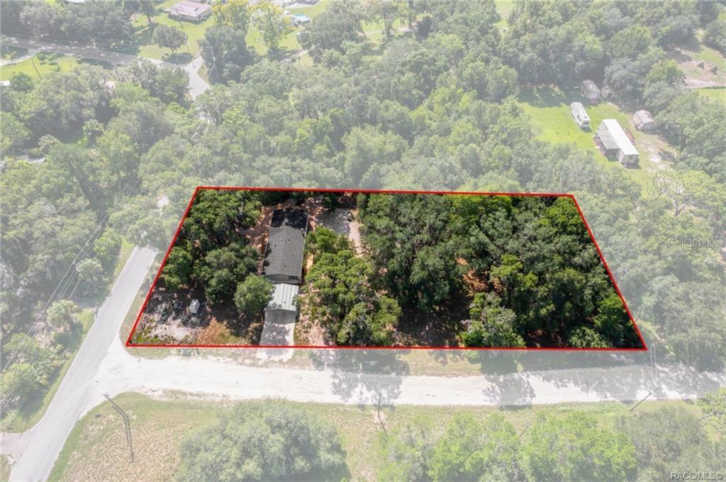 An aerial view shows a house with a metal carport on a wooded lot — 11437 N YOUNG DRIVE, DUNNELLON, FL