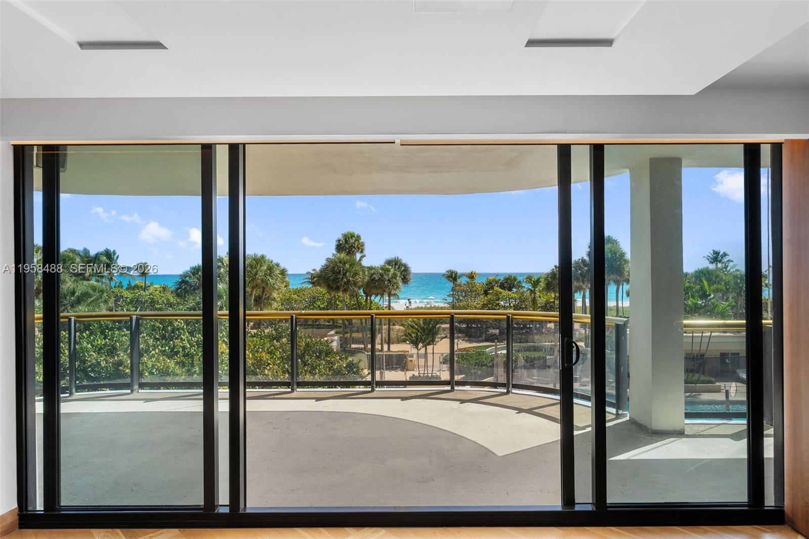 A view of a balcony and the ocean through large sliding glass doors — 9999 Collins Ave # 3E, Bal Harbour FL 33154, BAL HARBOUR, FL