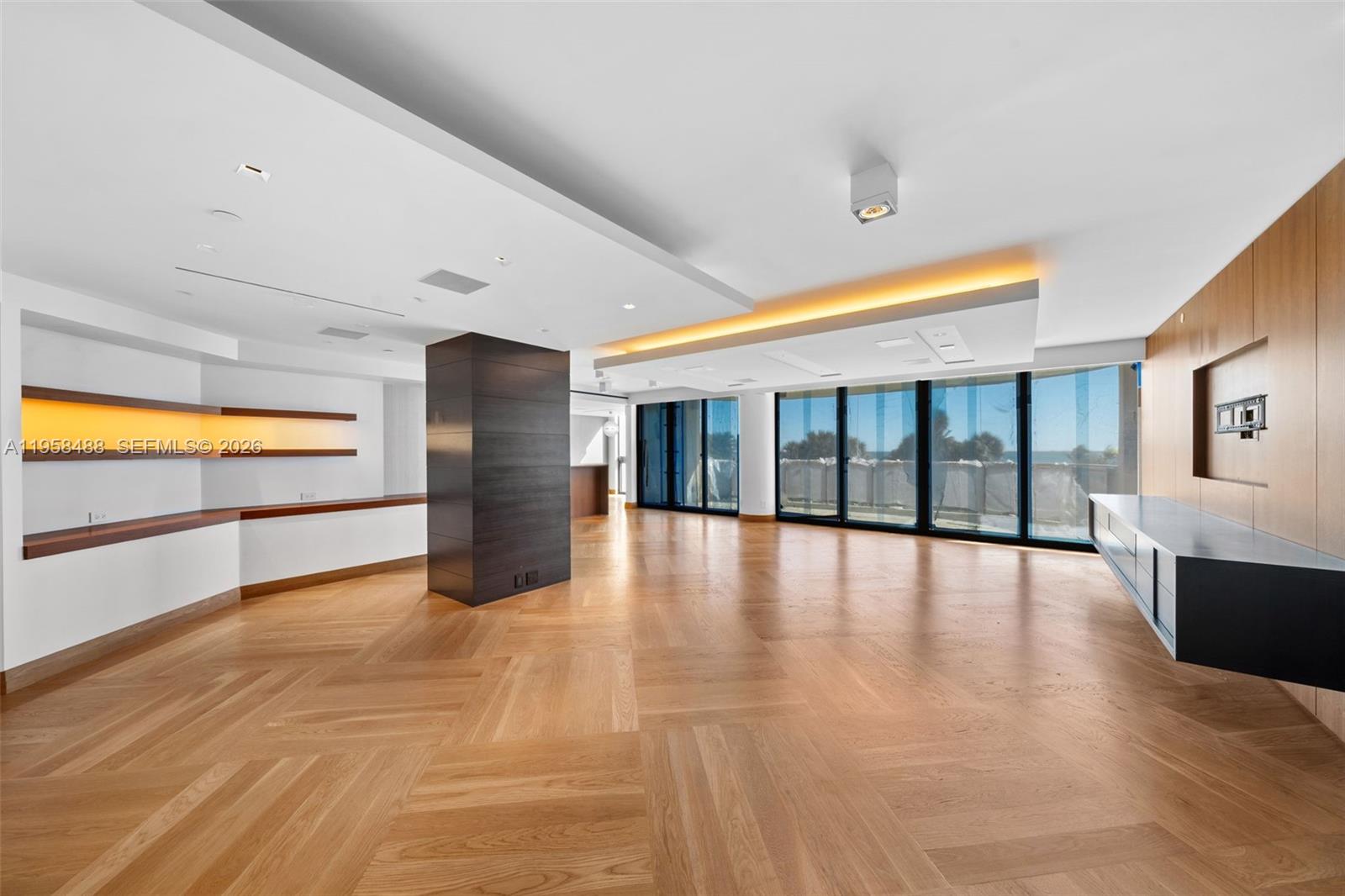 A spacious living area features herringbone wood floors, a dark central pillar, and floor-to-ceiling windows — 9999 Collins Ave # 3E, Bal Harbour FL 33154, BAL HARBOUR, FL