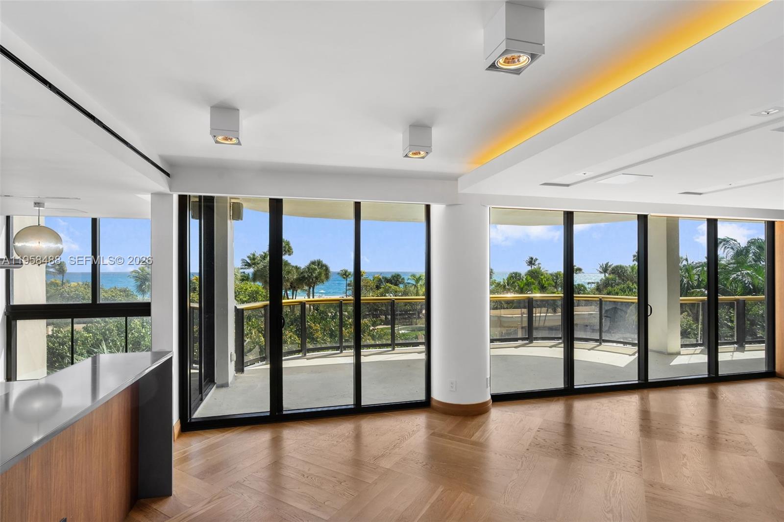 A bright living area features herringbone wood floors, recessed lighting, and floor-to-ceiling windows overlooking the ocean — 9999 Collins Ave # 3E, Bal Harbour FL 33154, BAL HARBOUR, FL